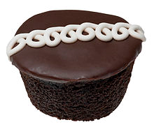 A chocolate Hostess CupCake, showing the chocolate cake and icing, and the signature line of white squiggles